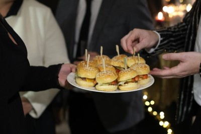Buffet avec amuse-bouches variés, boissons en carafes et seau à glace sur une table blanche en extérieur.