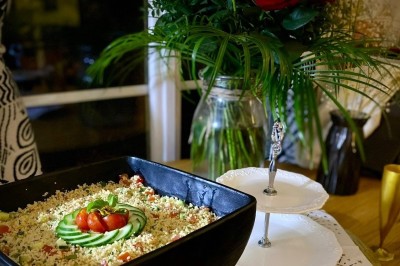 Buffet avec amuse-bouches variés, boissons en carafes et seau à glace sur une table blanche en extérieur.