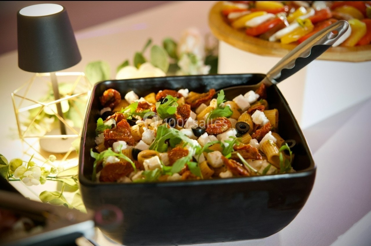 Salade méditerranéenne dans un bol noir, garnie de feta, tomates séchées, olives noires et roquette.