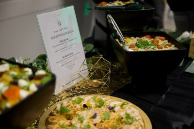 Buffet avec amuse-bouches variés, boissons en carafes et seau à glace sur une table blanche en extérieur.