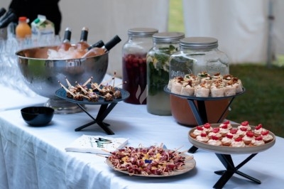 Buffet avec amuse-bouches variés, boissons en carafes et seau à glace contenant des bouteilles, disposé sur une table…