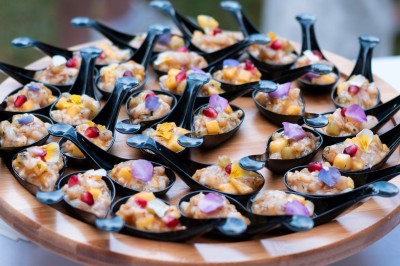 Buffet avec verrines, amuse-bouches, boissons en carafes et seau à glace sur une nappe blanche.