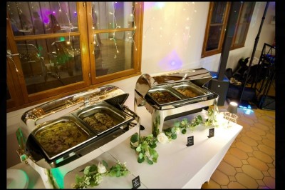 Buffet avec verrines, amuse-bouches, boissons en carafes et seau à glace sur une nappe blanche.