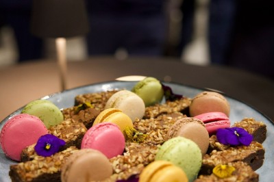 Buffet avec verrines, amuse-bouches, boissons en carafes et seau à glace sur une nappe blanche.