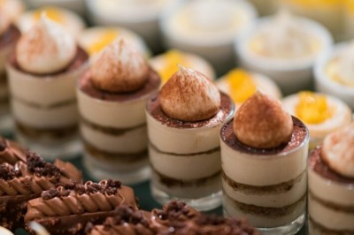 Buffet avec verrines, amuse-bouches, boissons en carafes et seau à glace sur une nappe blanche.