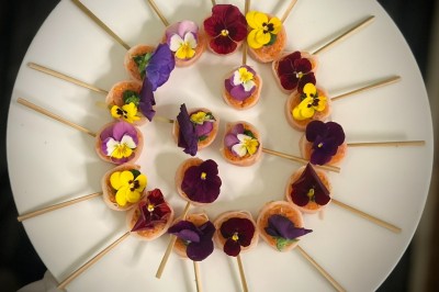 Buffet avec verrines, amuse-bouches, boissons en carafes et seau à glace sur une nappe blanche.