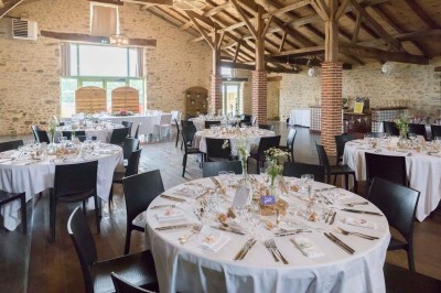 Salle à manger avec une grande table entourée de chaises, cuisine équipée à gauche et salon avec canapé au fond.