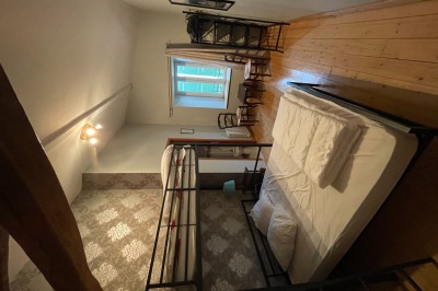 Salle à manger avec une grande table entourée de chaises, cuisine équipée à gauche et salon avec canapé au fond.