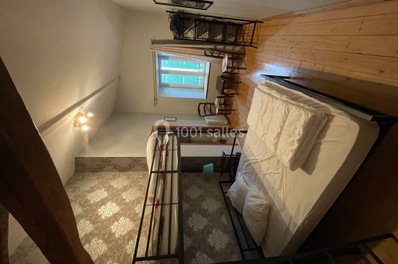 Chambre avec lits superposés et lit double, parquet au sol, fenêtre avec rideaux et mobilier en bois.