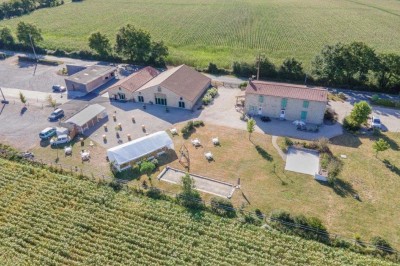 Salle à manger avec une grande table entourée de chaises, cuisine équipée à gauche et salon avec canapé au fond.