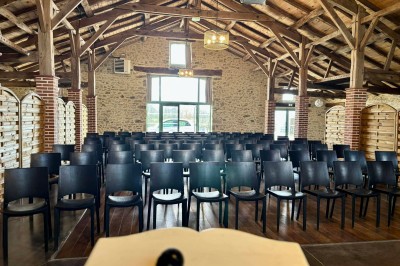 Salle à manger avec une grande table entourée de chaises, cuisine équipée à gauche et salon avec canapé au fond.