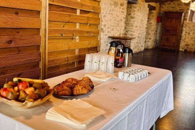 Salle à manger avec une grande table entourée de chaises, cuisine équipée à gauche et salon avec canapé au fond.