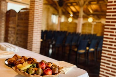 Salle à manger avec une grande table entourée de chaises, cuisine équipée à gauche et salon avec canapé au fond.