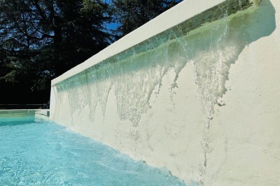 Piscine extérieure avec bassin principal et pataugeoire, entourée de chaises longues et d'arbres.