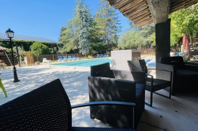 Piscine extérieure avec bassin principal et pataugeoire, entourée de chaises longues et d'arbres.