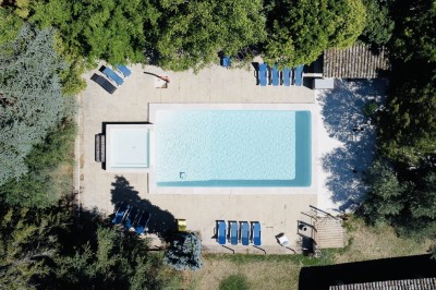 Piscine extérieure avec bassin principal et pataugeoire, entourée de chaises longues et d'arbres.
