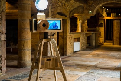 Téléphone rétro doré à cadran rotatif posé sur une surface blanche, avec un décor en bois et pierre en arrière-plan.