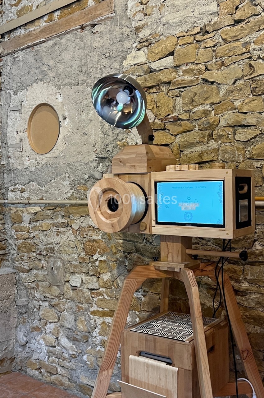Machine en bois avec écran tactile et lampe, installée devant un mur en pierre dans un espace intérieur rustique.