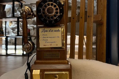 Une borne photo en bois avec écran et accessoires, entourée de personnes discutant dans un espace industriel.