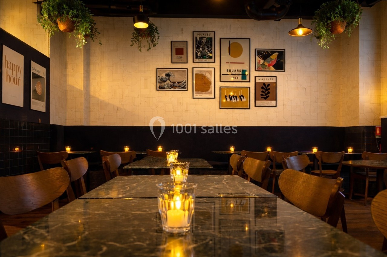 Salle de restaurant avec tables en marbre, chaises en bois, bougies allumées et décorations murales variées.