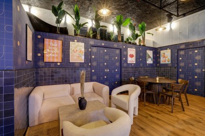 Intérieur d'un bar moderne avec comptoir éclairé, étagères de bouteilles, tables et chaises dans une ambiance chaleureuse.
