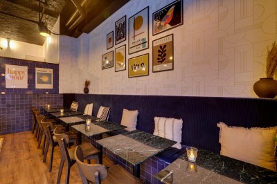 Intérieur d'un bar moderne avec comptoir éclairé, étagères de bouteilles, tables et chaises dans une ambiance chaleureuse.