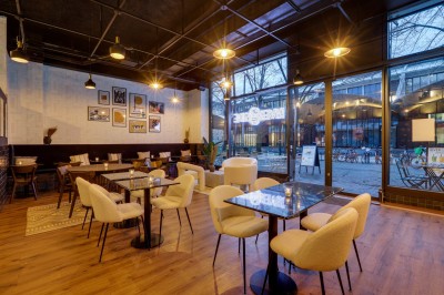 Intérieur d'un bar moderne avec comptoir éclairé, étagères de bouteilles, tables et chaises dans une ambiance chaleureuse.