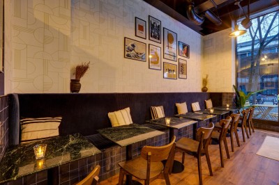 Intérieur d'un bar moderne avec comptoir éclairé, étagères de bouteilles, tables et chaises dans une ambiance chaleureuse.