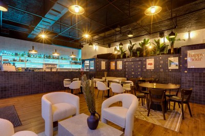 Intérieur d'un bar moderne avec comptoir éclairé, étagères de bouteilles, tables et chaises dans une ambiance chaleureuse.