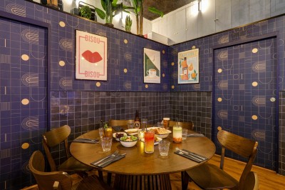 Intérieur d'un bar moderne avec comptoir éclairé, étagères de bouteilles, tables et chaises dans une ambiance chaleureuse.