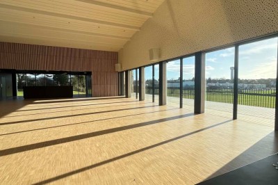 Cuisine professionnelle équipée avec plan de travail inox, fours, hotte, micro-ondes et sol carrelé gris.