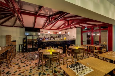 Miniature Location salle Maisons-Alfort (Val-de-Marne) - Fabbrezza Maisons-Alfort #2 Bar avec comptoir en carrelage sombre, tabourets en bois, étagères avec bouteilles et verres, éclairage suspendu.