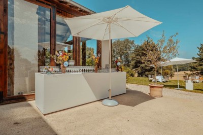Vue d'une table élégamment dressée avec des verres, des couverts et un bouquet de fleurs colorées au centre.