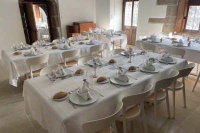 Vue aérienne d'un manoir en pierre entouré de champs et de végétation, avec un village et la mer à l'horizon.