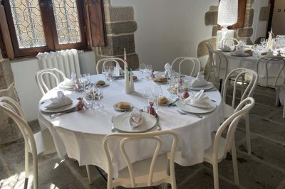 Vue aérienne d'un manoir en pierre entouré de champs et de végétation, avec un village et la mer à l'horizon.