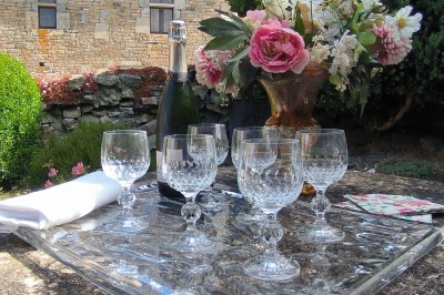 Vue aérienne d'un manoir en pierre entouré de champs et de végétation, avec un village et la mer à l'horizon.