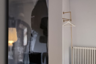 Vue aérienne d'un manoir en pierre entouré de champs et de végétation, avec un village et la mer à l'horizon.