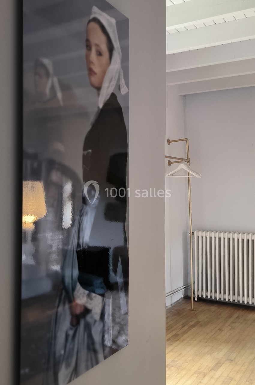 Photographie d'un tableau représentant une femme en tenue traditionnelle, accrochée dans une pièce lumineuse et épurée.