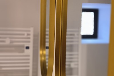 Vue aérienne d'un manoir en pierre entouré de champs et de végétation, avec un village et la mer à l'horizon.