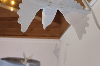 Vue aérienne d'un manoir en pierre entouré de champs et de végétation, avec un village et la mer à l'horizon.