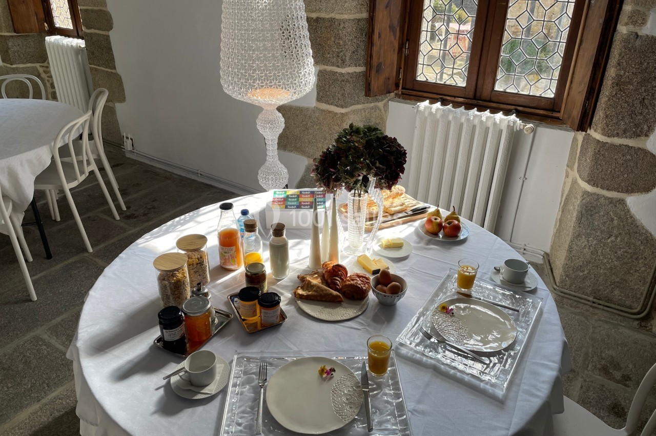 Table dressée pour un petit-déjeuner avec viennoiseries, jus d'orange, confitures et décorations dans une salle lumineuse.