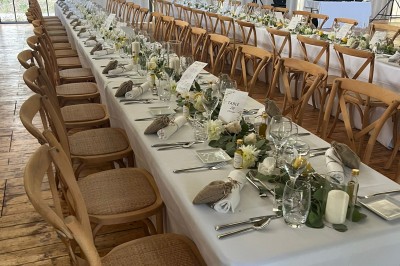 Table dressée avec nappes blanches, vaisselle vintage, chandeliers et décorations florales séchées.