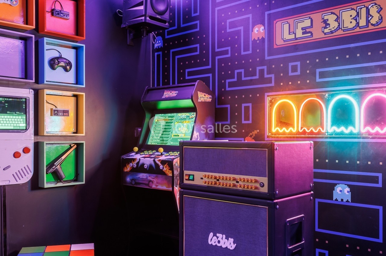 Salle rétro-gaming avec borne d'arcade, amplificateurs, décorations néon et étagères d'objets vintage colorés.