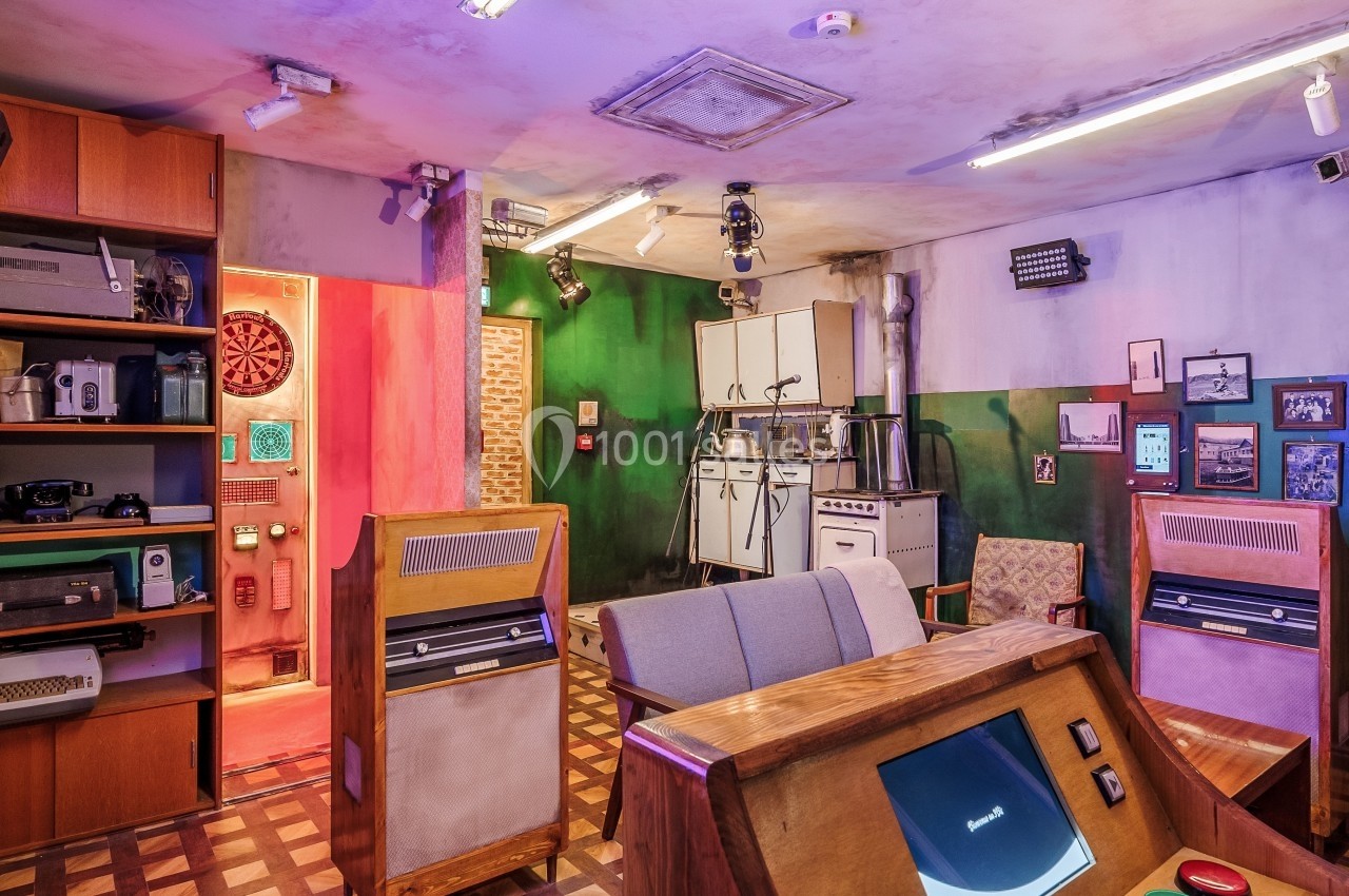 Salle rétro avec mobilier en bois, équipements électroniques vintage, éclairage coloré et décorations murales variées.