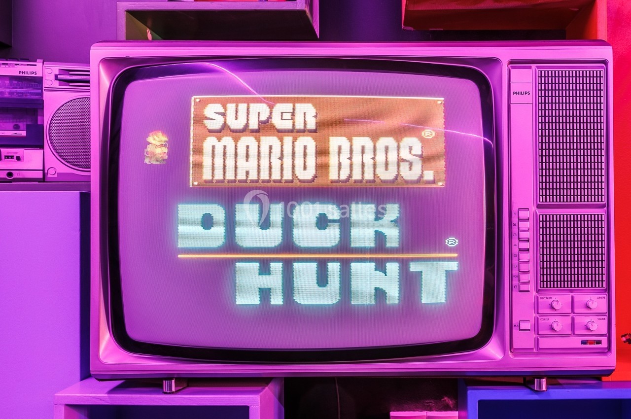 Écran cathodique affichant le titre des jeux ’Super Mario Bros.’ et ’Duck Hunt’ dans un décor rétro coloré.
