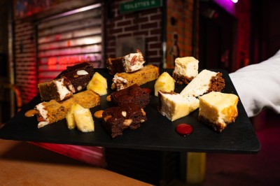 Miniature Location salle Paris 13 (Paris) - Le 3bis #34 Assortiment de desserts variés, incluant brownies, cheesecake et autres pâtisseries, présenté sur une ardoise noire.