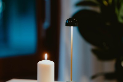 Terrasse ensoleillée avec tables rondes blanches, chaises et coussins jaunes, vue sur des toits et des arbres.