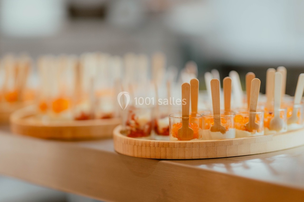 Plateaux en bois garnis de verrines colorées avec des cuillères en bois, disposés sur une table.