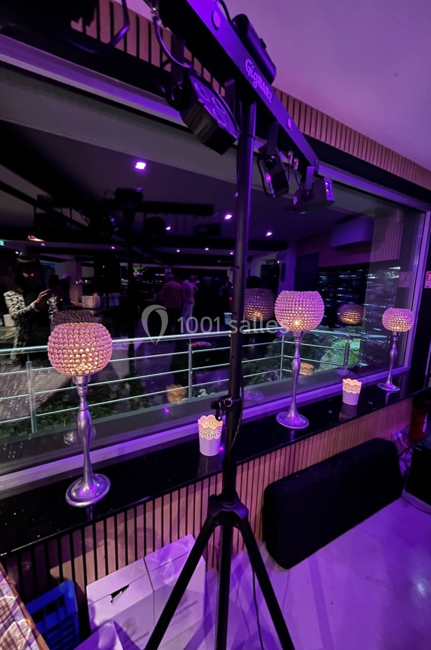 Lampes décoratives à cristaux allumées devant une baie vitrée, avec vue sur une terrasse et des lumières nocturnes.