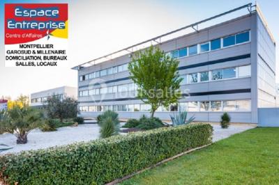 Bâtiment moderne entouré de végétation, avec un panneau indiquant ’Espace Entreprise Centre d'Affaires’ à Montpellier.